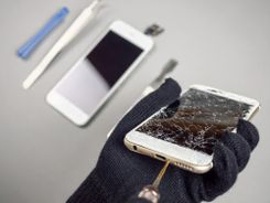 mano con guante reparando smartphone en pantalla quebrada